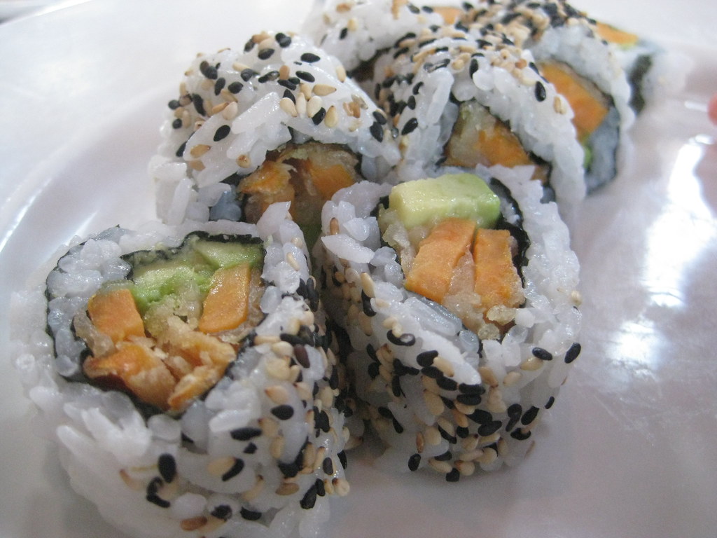Inside-out sushi roll with sweet potato tempura and avocado, coated in sesame seeds